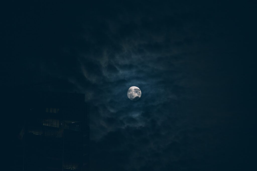Moon in the 3rd house represented in a dark and cloudy sky.