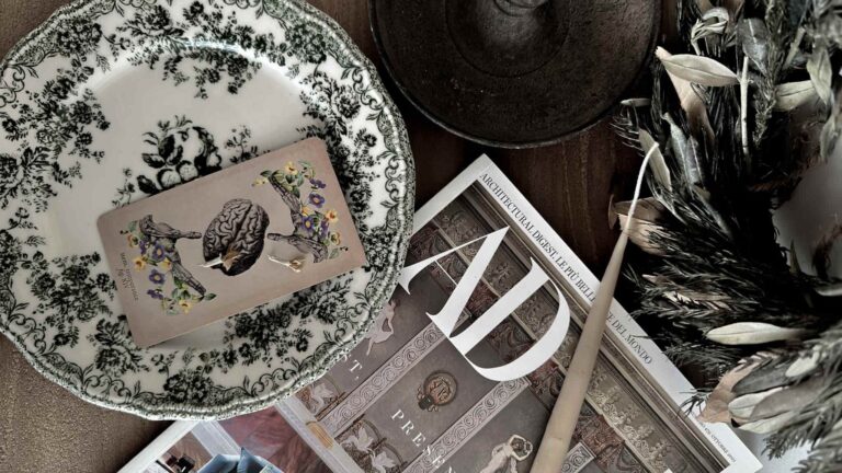 Must Tarot cards be gifted? Legend & Modern perspectives able setting featuring a tarot card, a design-related journal, and aesthetic details.