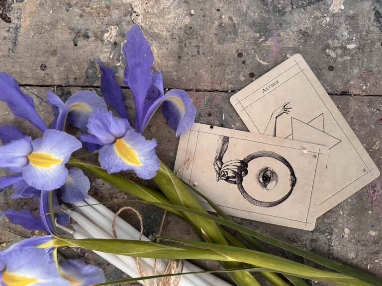 Cards from one of the best oracle deck arranged on a table alongside vibrant purple flowers.