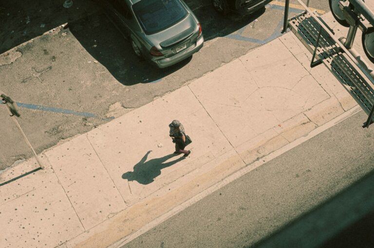 Virgo Season 2025: Energy Shifts & Your DO/DON’T Horoscope A lone person walking on a sunlit sidewalk casting a long shadow, symbolizing reflection and transition during Virgo Season 2025.