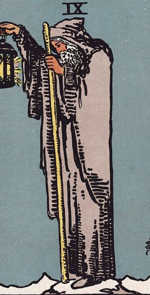 The Hermit card from the Rider-Waite tarot, showing an old man with a lantern and staff standing on a mountain.