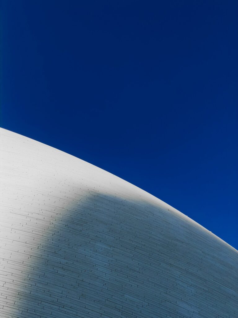 Neptune’s Influence Over the Last 50 Years Neptune’s transits over the last 50 years symbolized through a minimalist white curved structure against a deep blue sky.