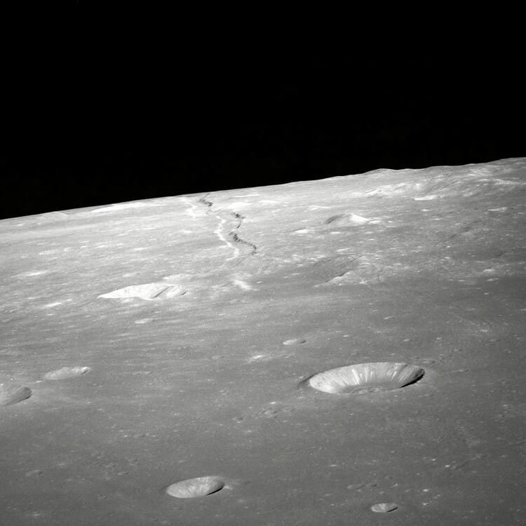 Moon surface with craters and shadowed horizon.