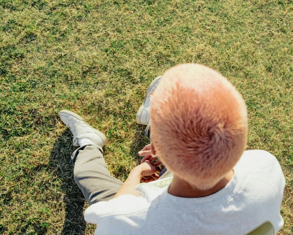 Mars in Pisces introspective mood, person with pink hair sitting alone on grass