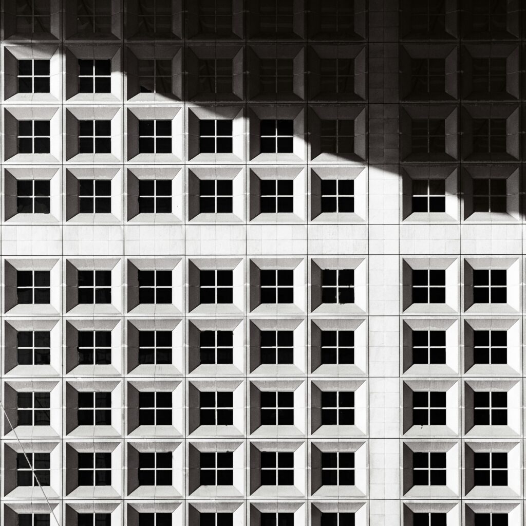 Grand Cross aspect in astrology represented by a black and white photograph of a building façade with a geometric pattern and a strong, dramatic shadow.