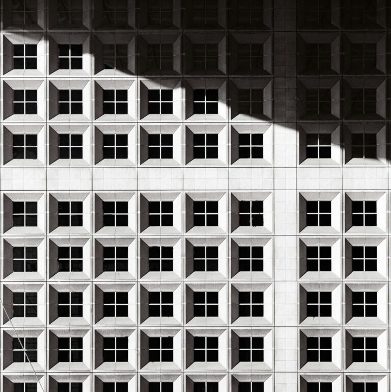 Grand Cross aspect in astrology represented by a black and white photograph of a building façade with a geometric pattern and a strong, dramatic shadow.