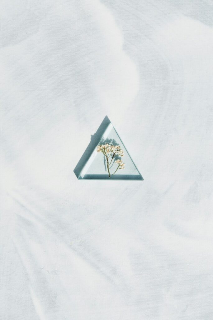 Trine aspect in astrology symbolised by a glass triangle holding a small flower.