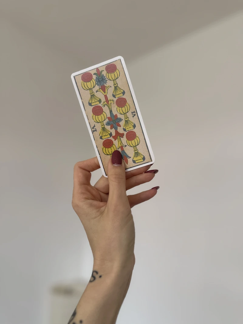 Six of cups tarot marseille card held in hand.