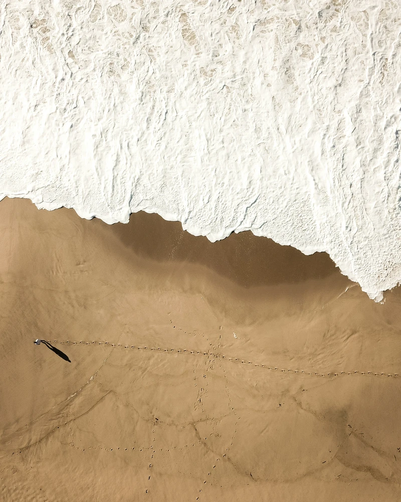 Scorpio Full Moon aerial view of sand meeting water, symbolizing emotional depth, fluidity, and the hidden layers of the water element.