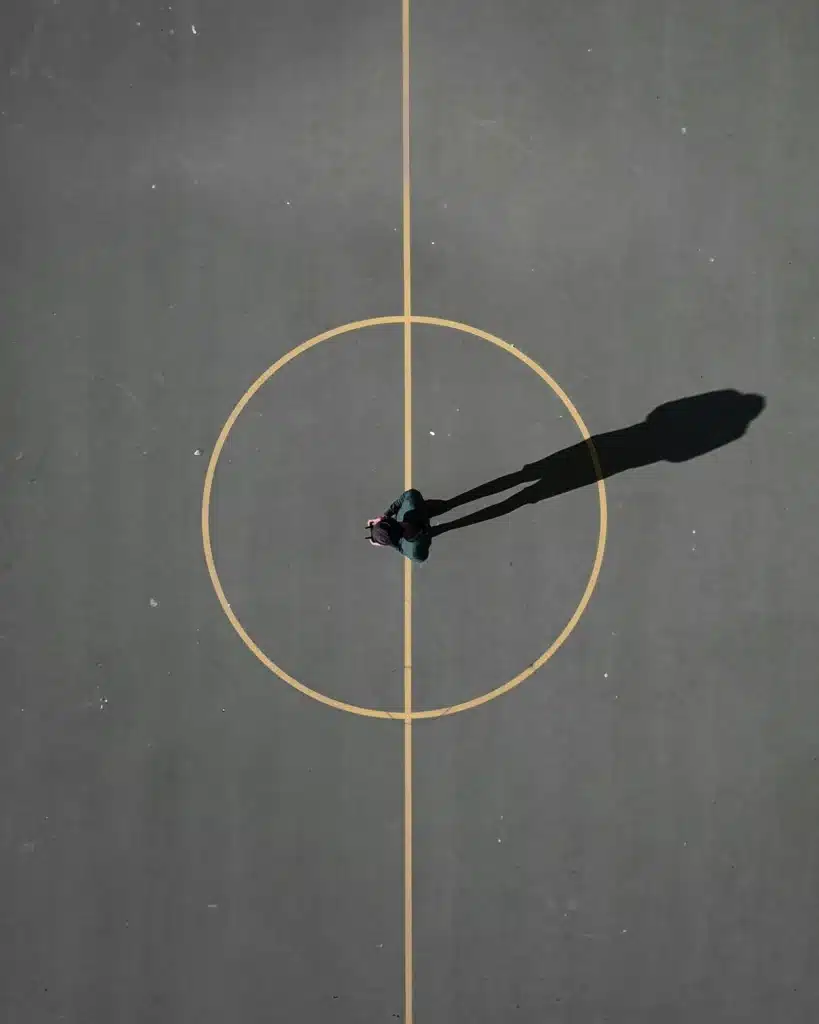 Horoscopes symbolism seen from above: a circular road with a man standing at the center, evoking the zodiac wheel.