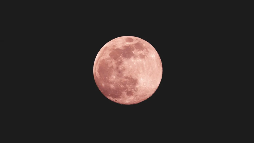 Libra Full Moon also called Pink Moon rising in the night sky with a soft pink glow.