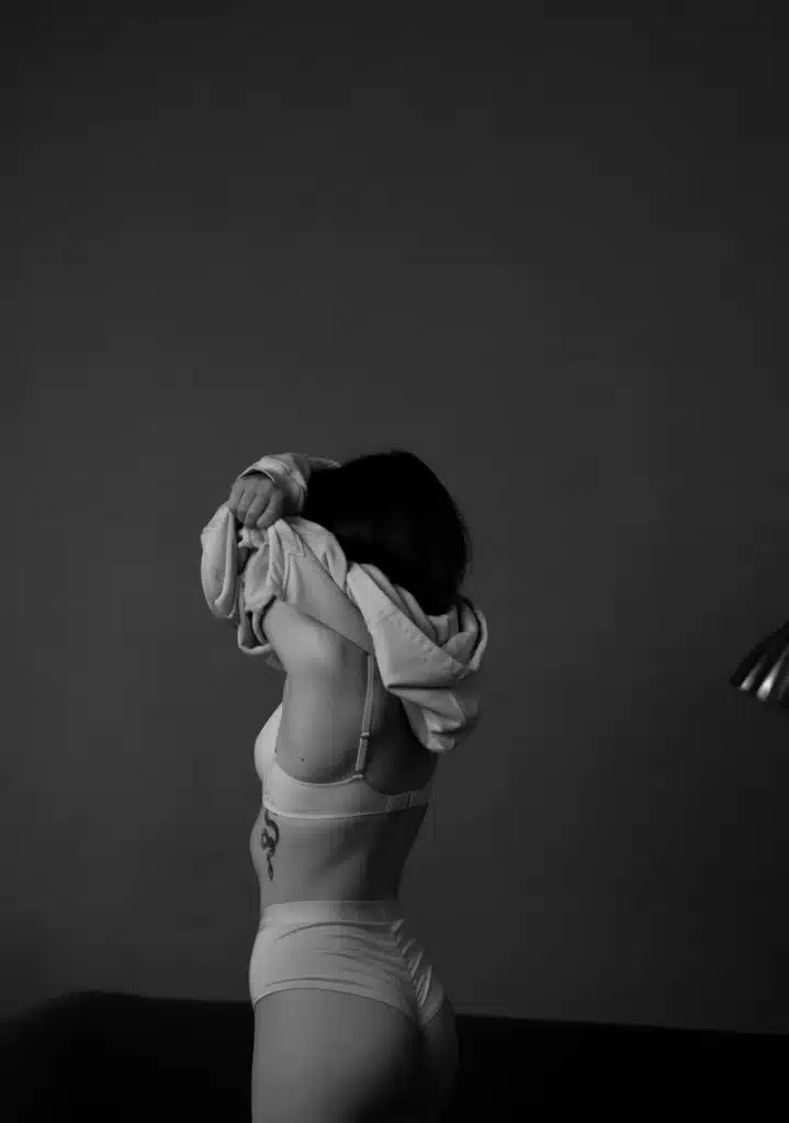 aries rising transformation: a woman from behind removing her clothing, symbolizing vulnerability, identity, and the revealing nature of the Ascendant
