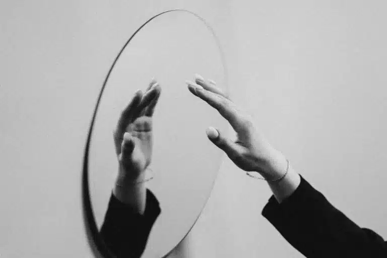 aries rising representation in black and white, hands reaching toward a mirror symbolizing the Ascendant as the first perception of the self