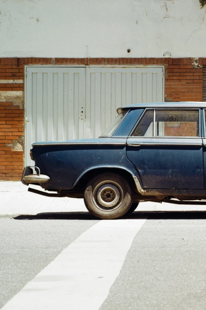 Vintage car parked on a quiet street in soft natural light, street photography style evoking movement and everyday curiosity linked to Gemini energy