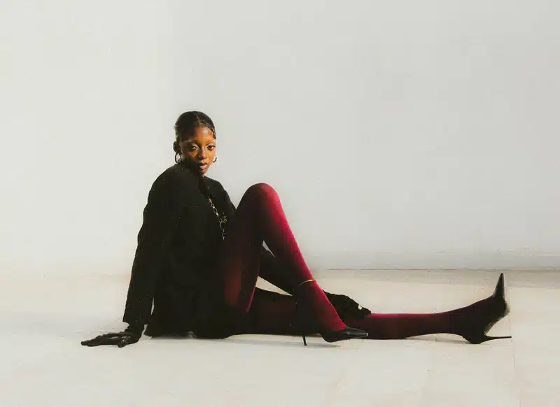 taurus rising sensual elegance woman seated in black on a white background, symbolizing grounded beauty and confidence.