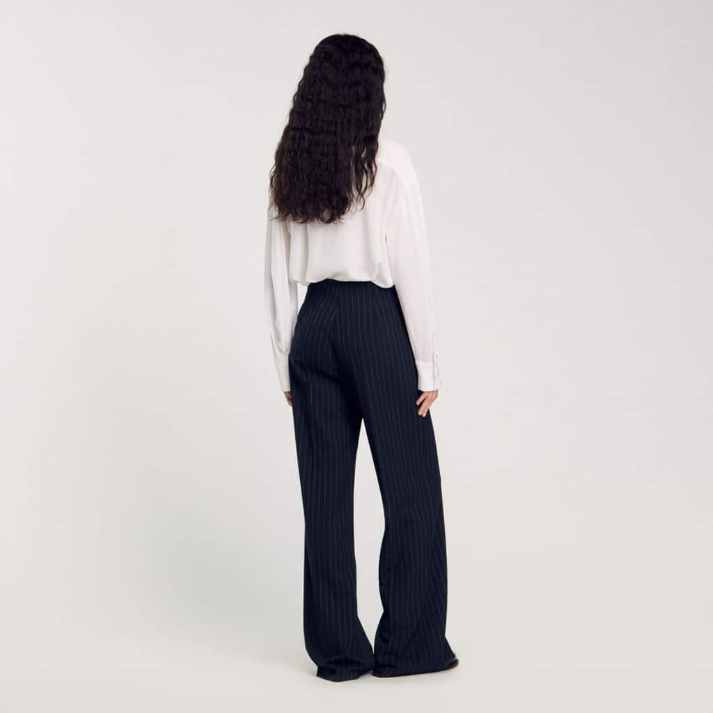 sandro paris pinstripe trousers libra rising style, woman seen from behind wearing tailored pants with clean lines, elegant and balanced silhouette