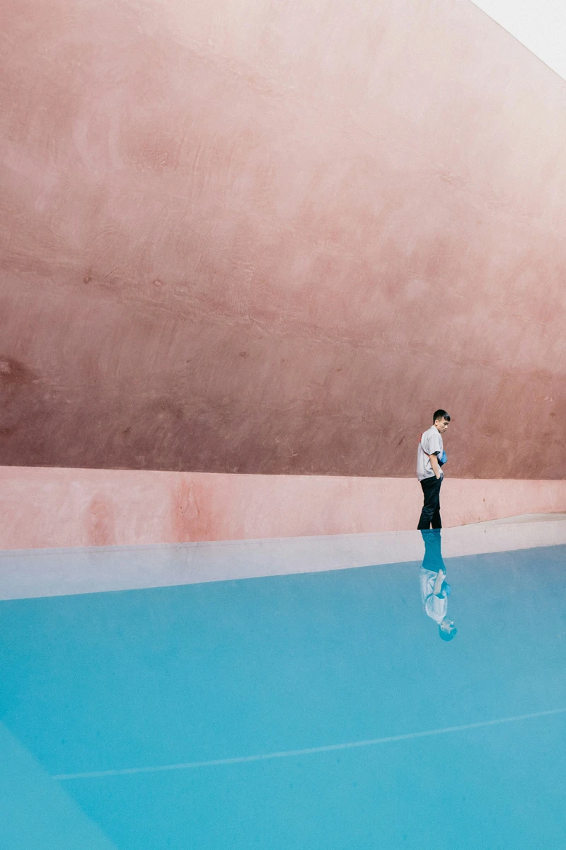 sagittarius rising street photography with a person walking across a blue pavement and pink wall background, vibrant movement and playful expansive atmosphere