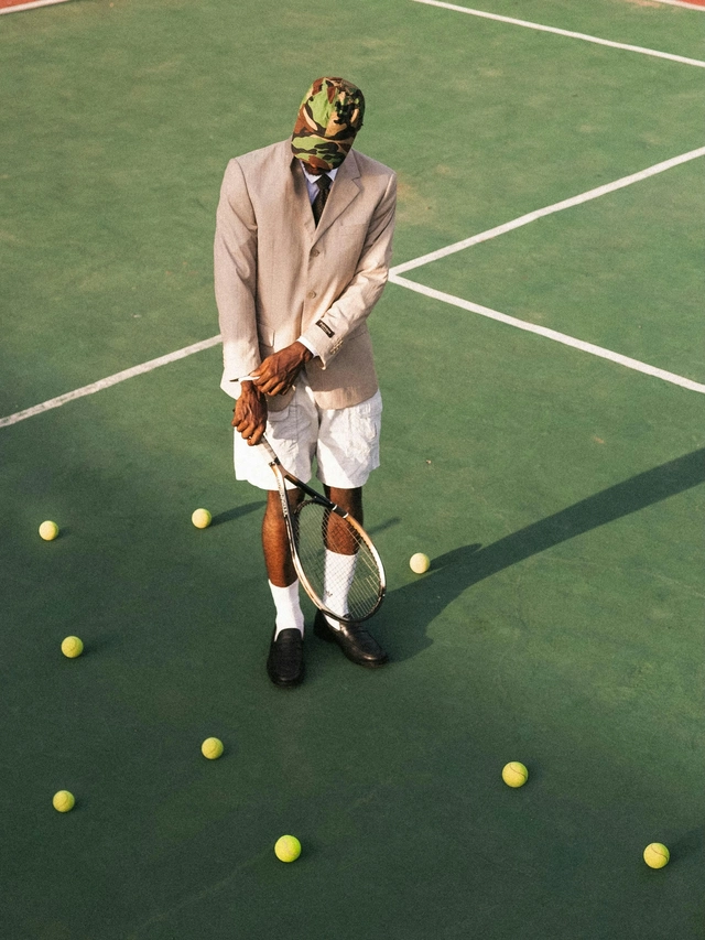 Eccentric astrology placements and aspects symbolized by a young man holding a tennis racket in the middle of a tennis court while wearing a formal jacket.