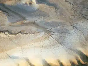 Virgo New Moon reflected in an aerial view of a textured desert landscape in soft beige and blue-grey tones, evoking grounded Earth energy.