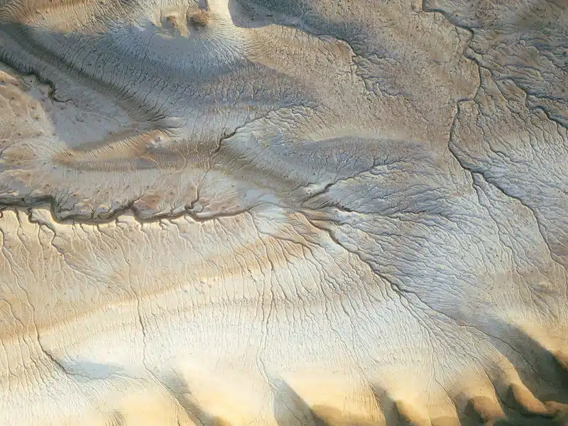 Virgo New Moon: Meaning, Energy and How It Affects Each Zodiac Sign Virgo New Moon reflected in an aerial view of a textured desert landscape in soft beige and blue-grey tones, evoking grounded Earth energy.