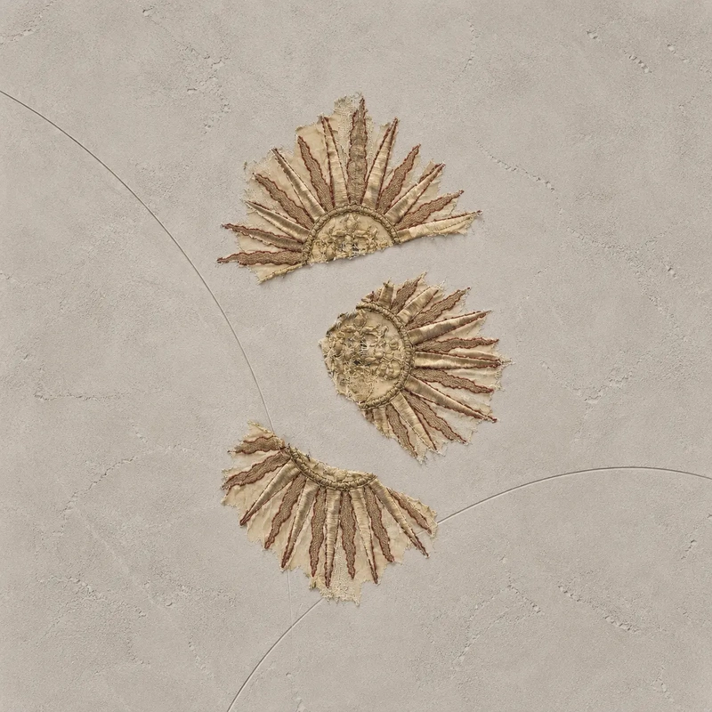 Three golden embroidered sunburst motifs on a textured ivory background, symbolising the Sun, Moon and Rising signs explored in a personalised Big Three astrology reading.