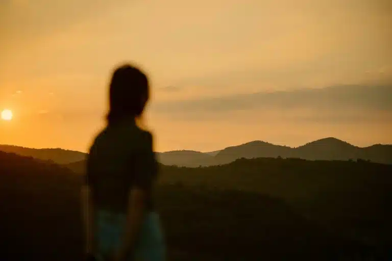 Mars enters Leo, represented by a silhouetted figure standing before a fiery golden sunset and distant hills.