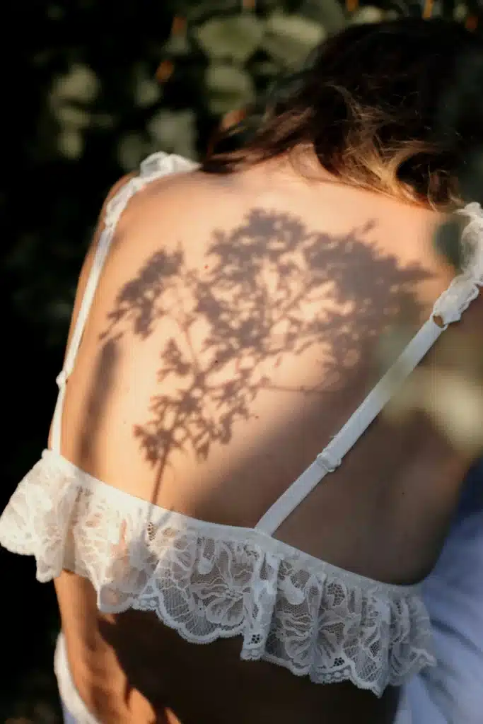 Mars in Leo energy represented by sunlight and the shadow of a flowering plant cast across a woman’s back.