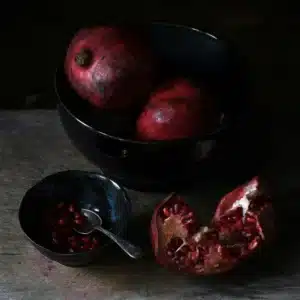 Venus in Scorpio symbolised by dark red pomegranates arranged in black bowls, evoking Persephone and the Underworld.