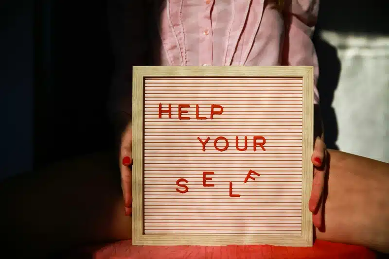Sign reading “Help Yourself” in red letters, symbolizing self-awareness, inner guidance, and the birth chart as a tool for personal understanding.