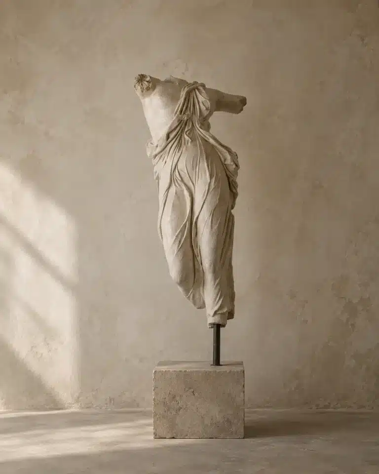 Full Moon in Taurus image with a classical headless statue on a stone pedestal against a warm wabi sabi wall, evoking grounding, stillness, beauty, and earthy stability.