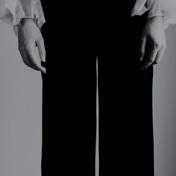 Black-and-white artistic photo showing Billie Eilish’s hands and part of her outfit, used as the featured image for her birth chart astrology article.