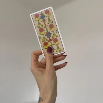 Six of cups tarot marseille card held in hand.