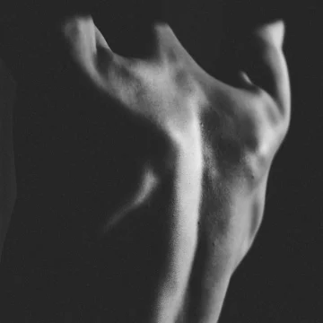 capricorn rising black and white photograph of a bare back, minimalist composition expressing strength, restraint, and quiet vulnerability