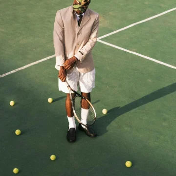 Eccentric astrology placements and aspects symbolized by a young man holding a tennis racket in the middle of a tennis court while wearing a formal jacket.