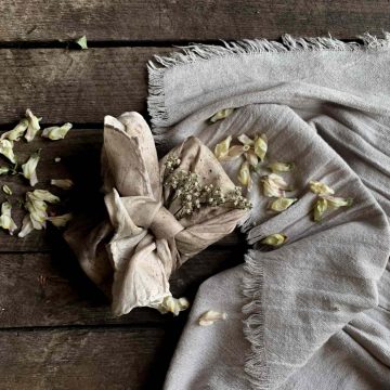 The chosen Tarot deck carefully wrapped in white fabric with surrounding petals.