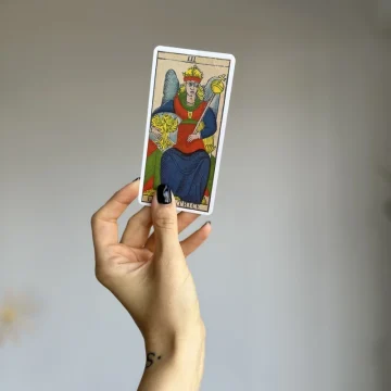how to shuffle tarot cards hand holding a tarot card in a calm, focused moment before a reading