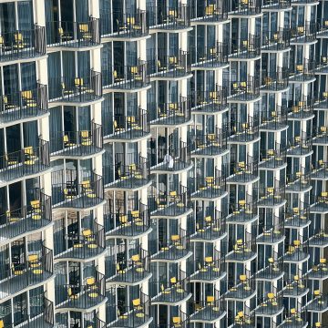 Mars in Capricorn: a building façade with repeating balconies and yellow chairs, symbolizing organized effort.