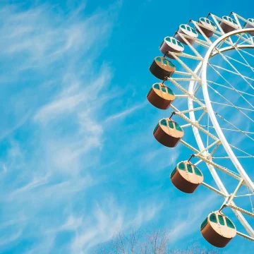 Neptune in the 7th House symbolism, ferris wheel against a blue sky representing idealism, shifting perspectives, and the dreamlike nature of relationships and partnerships.