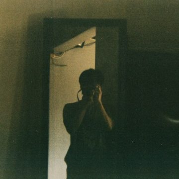 Neptune in the 1st House, a blurred figure reflected in a dimly lit mirror, symbolizing a fluid sense of identity and Neptune’s dissolving, mystical influence.