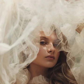pisces rising ethereal portrait of a woman surrounded by cloud-like fabric, dreamy emotional atmosphere with soft mystical and poetic aesthetic