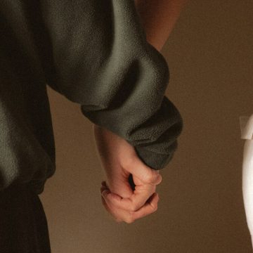 Two people holding hands, symbolizing connection and compatibility in love.