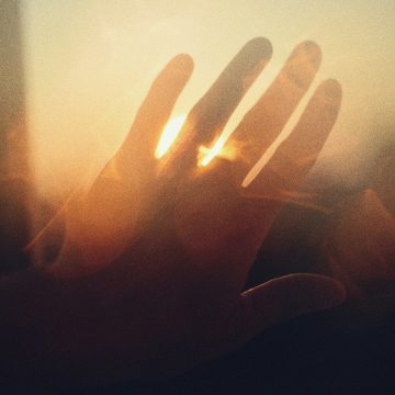 Rising sign astrology concept illustrated by a hand reaching toward sunlight