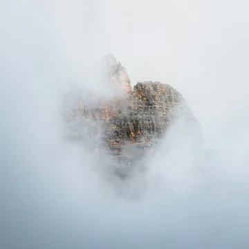 Saturn in Gemini birth chart symbolism represented by a mountain emerging through soft mist and clouds.