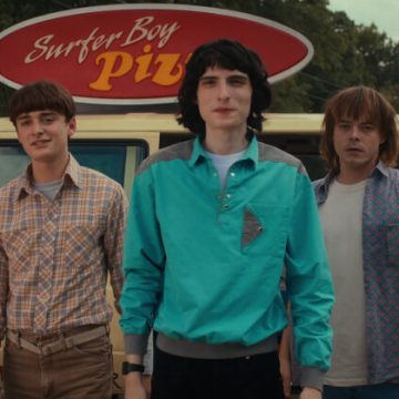 The Stranger Things main group standing together outside a Surfer Boy Pizza van.