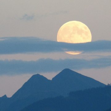 Moon in the 9th house depicted by a massive full moon over the mountains.