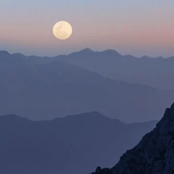 Moon in the 10th house depicted by a shining full moon over the mountains.