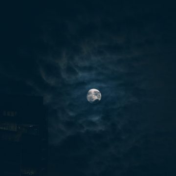 Moon in the 3rd house represented in a dark and cloudy sky.