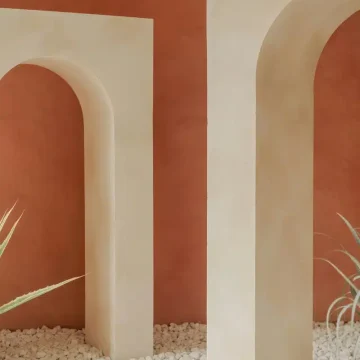 Venus in Virgo transit symbolized by minimal architectural arches on a quiet red wall, evoking refined beauty, silence, balance, and love expressed through careful simplicity.