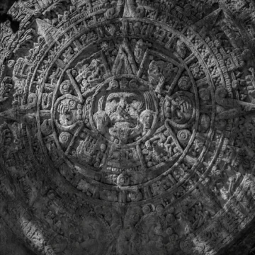 Mayan signs carved into an ancient Mayan calendar stone, black and white close-up showing detailed symbols of the sacred Tzolk'in.